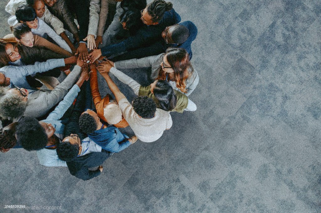 A diverse business team showing collaboration and unity with hands joined together in a team-building exercise.